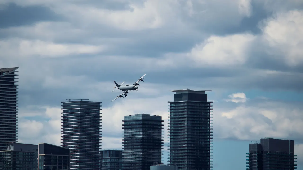 A four-engine aircraft banking over a city skyline.
