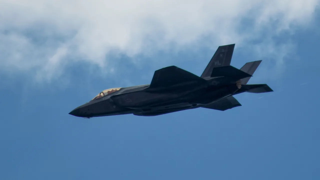 A dark fighter jet climbing through a blue sky.