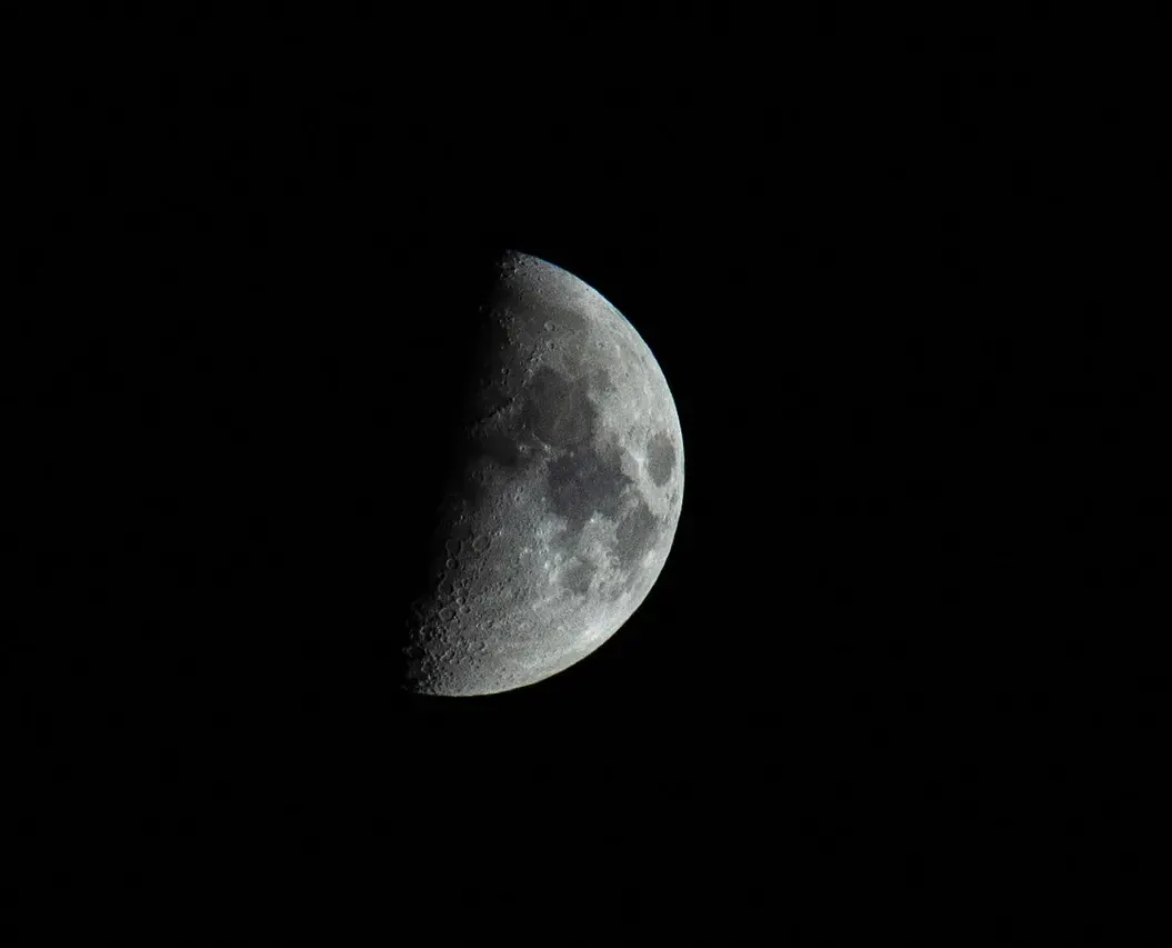 A half-lit moon on a black sky.