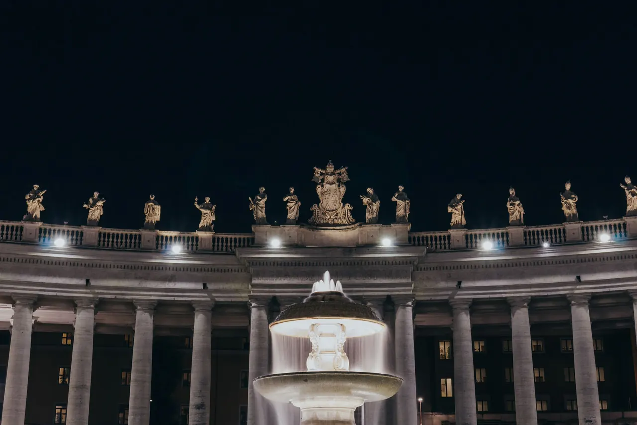 The colonnade and fountain in St. Peter's Square at night.